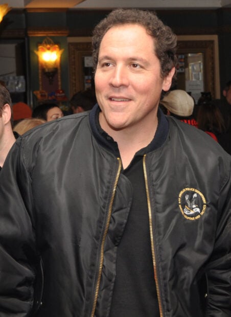 Jon Favreau is wearing a black jacket and smiling in a crowded indoor setting, HD Phone Wallpaper