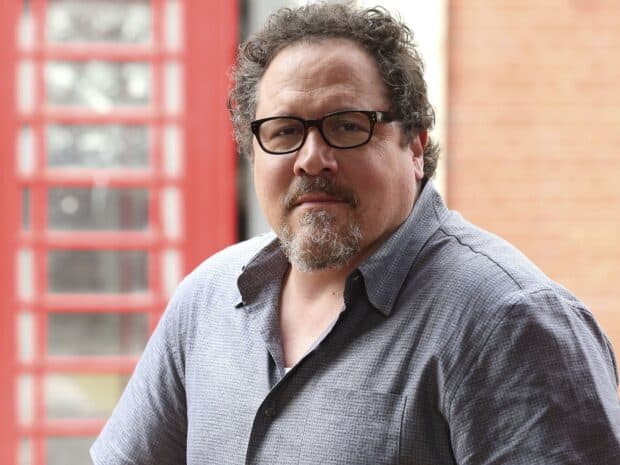 Jon Favreau wallpapers shows him wearing glasses and a grey shirt with a red structure background, HD Desktop Wallpaper