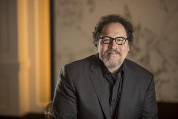 Jon Favreau smiles warmly wearing glasses and a suit in a professional setting, HD Desktop Wallpaper
