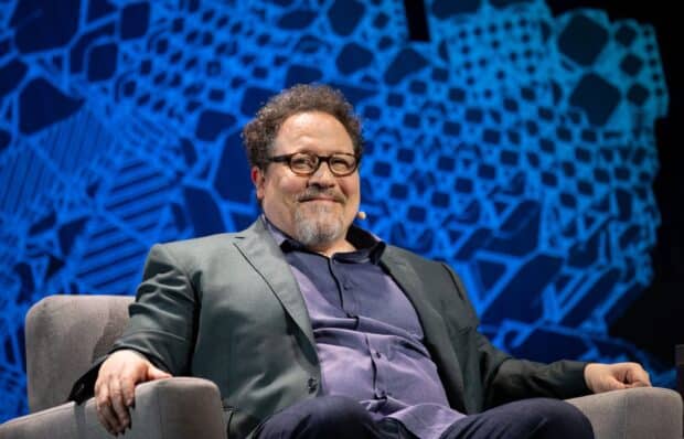 Jon Favreau is sitting and smiling during a speaking event, HD Desktop Wallpaper