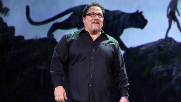 Jon Favreau is standing in front of a backdrop with a silhouette of a panther, HD Desktop Wallpaper