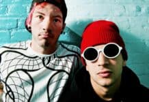 Josh Dun and a bandmate posing in front of a turquoise wall with distinctive clothing and accessories, HD Desktop Wallpaper