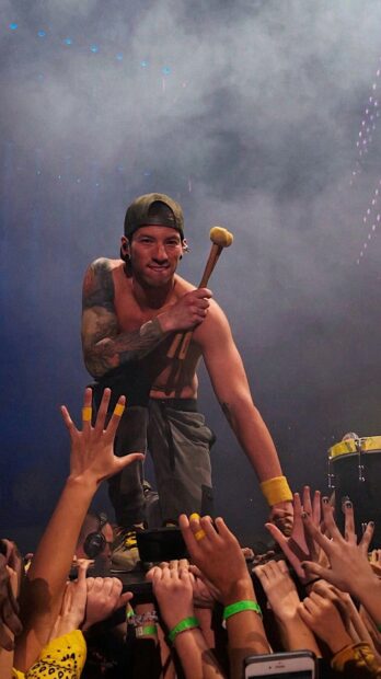 Josh Dun holding drumsticks while engaging with fans during a concert, HD Mobile Wallpaper