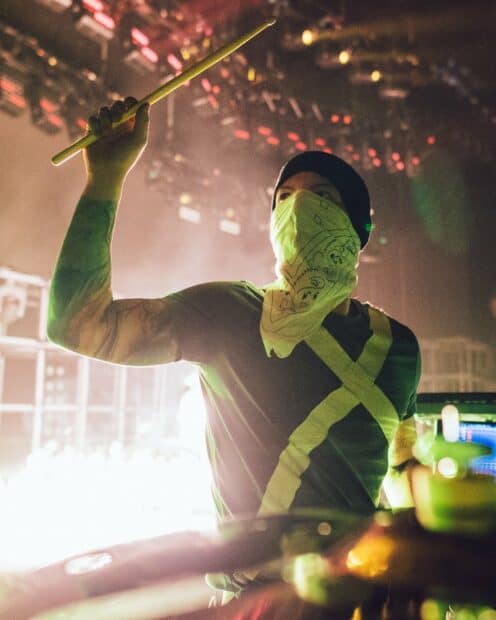 A drummer wearing a bandana and beanie plays drums during a concert in bright lights featuring Josh Dun wallpapers, HD Mobile Wallpaper