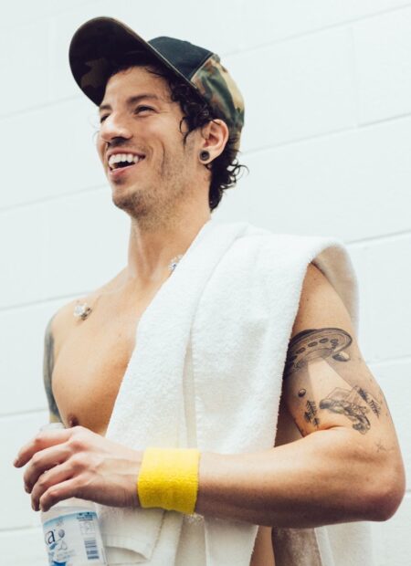 Josh Dun Wallpapers shows a man smiling while holding a water bottle and wearing a towel and cap, HD Mobile Wallpaper