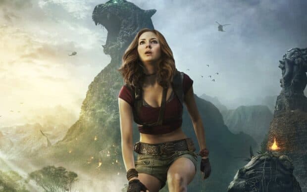A woman in action gear stands in a jungle landscape with a giant stone statue behind, HD Desktop Wallpaper