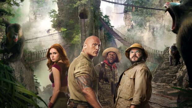 The main characters of Jumanji The Next Level stand alert in a misty jungle setting with monkeys around, 2K Desktop Wallpaper