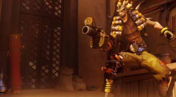 Junkrat is captured in a dynamic pose holding explosives inside a dimly lit room, 2K Desktop Wallpaper
