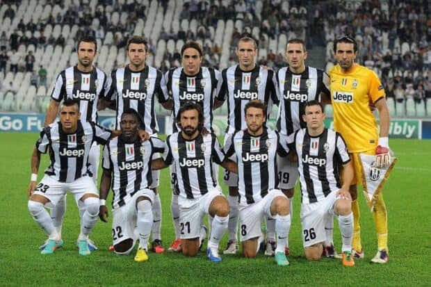 A group photo of Juventus players wearing black and white striped jerseys standing and kneeling on the football field, HD Desktop Wallpaper
