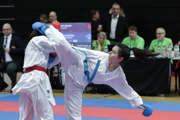 A female athlete executes a high kick in a karate match with focused determination, HD Desktop Wallpaper