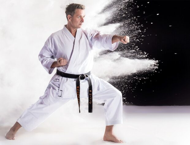 A karate expert is shown executing a strong punch with powder explosively spreading behind, HD Desktop Wallpaper