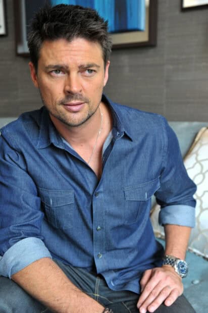 A portrait of Karl Urban wearing a blue shirt while sitting on a couch, HD Phone Wallpaper