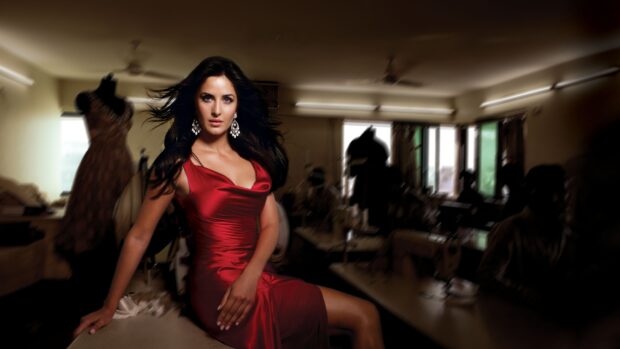 Katrina Kaif in an elegant red dress sitting in a dimly lit room surrounded by sewing mannequins, 4K Desktop Wallpaper