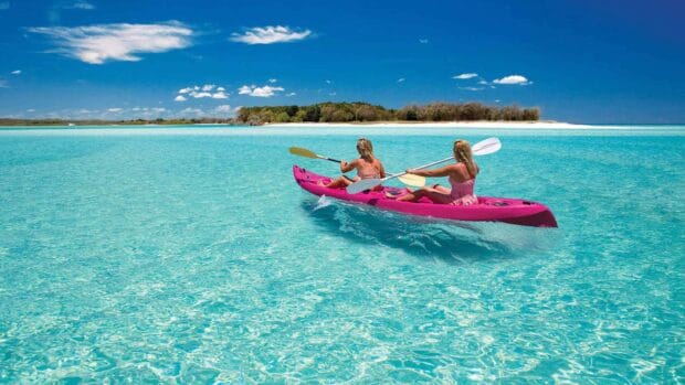 Two women kayaking on clear blue water near Fraser Island with island in background, HD Desktop Wallpaper