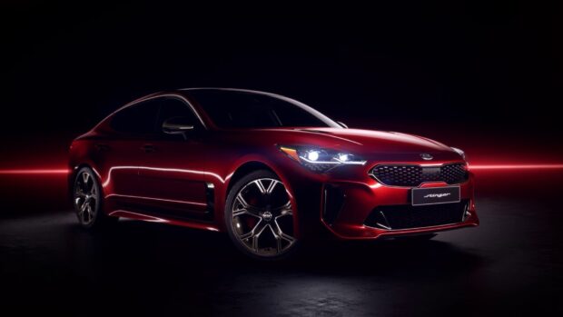 A sleek red Kia Stinger with illuminated headlights in a dark setting, HD Desktop Wallpaper