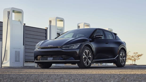 A black Kia electric car is parked at a charging station during sunset, HD Desktop Wallpaper