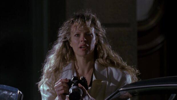Kim Basinger holds a Nikon camera with a serious expression at night, HD Desktop Wallpaper