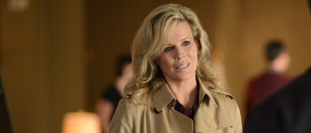 Kim Basinger shows a thoughtful expression wearing a beige coat in an indoor setting, 2K Desktop Wallpaper