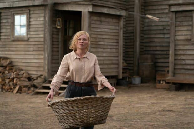 A woman holding a large woven basket stands outside a wooden building in a rural setting with Kirsten Dunst wallpapers, HD Desktop Wallpaper