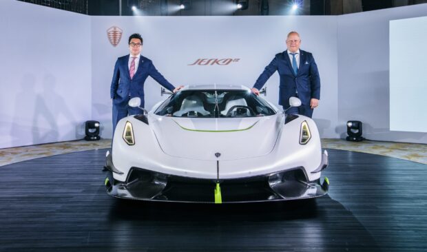 Two men stand beside a white Koenigsegg car at a launch event showcasing Koenigsegg wallpapers, 2K Desktop Wallpaper