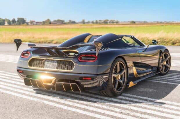 A Koenigsegg showcasing sleek black and gold design parked on a runway, 2K Desktop Wallpaper