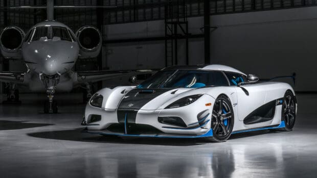 A white and blue Koenigsegg is parked inside a hangar next to a private jet, 4K Desktop Wallpaper