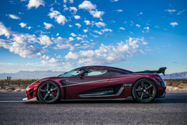A Koenigsegg is shown parked on a desert road under a blue sky with clouds, HD Desktop Wallpaper
