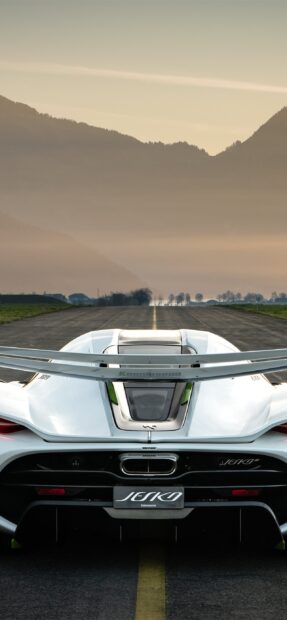 A rear view of a Koenigsegg sports car parked on a runway with mountains in the background, 2K Phone Wallpaper