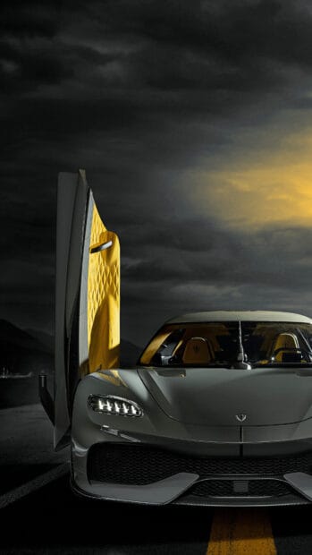 A Koenigsegg with its yellow interior door open is parked under a dramatic cloudy sky, 4K Phone Wallpaper