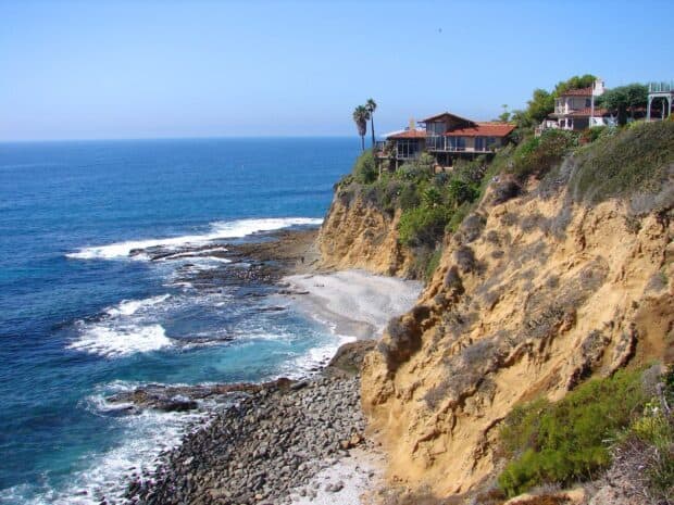 Laguna Beach reveals rocky cliffs with ocean waves and seaside houses, 2K Desktop Wallpaper