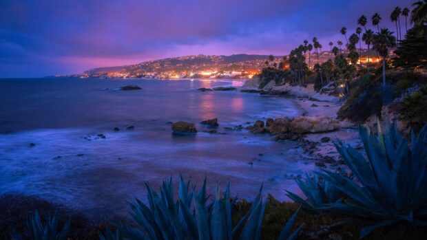 The Laguna Beach shows vibrant colors over the sea and rocky shore at dusk, 4K Desktop Wallpaper