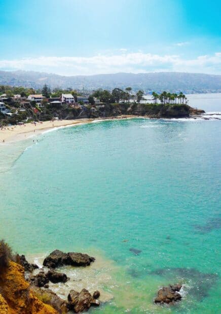 The Laguna Beach coastline shows clear turquoise water and rocky shores under a blue sky, HD Mobile Wallpaper