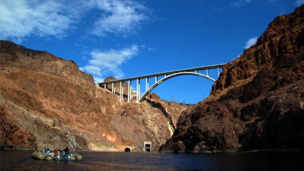 A boat floats on Lake Mead with the bridge and rocky canyon in the background, HD Desktop Wallpaper