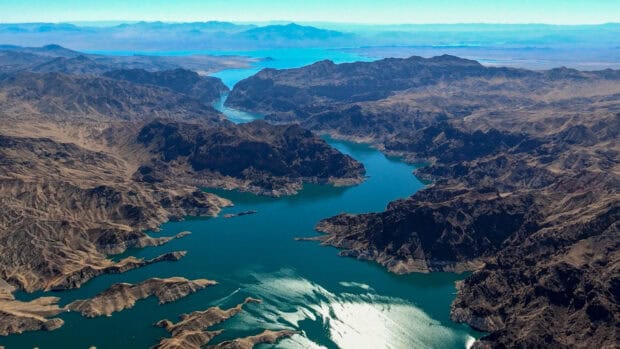 The Lake Mead features a winding river surrounded by rugged mountains under a clear sky, 2K Desktop Wallpaper