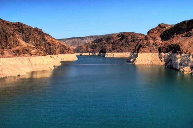 The calm blue waters of Lake Mead surrounded by rugged rocky cliffs under a clear sky, 2K Desktop Wallpaper