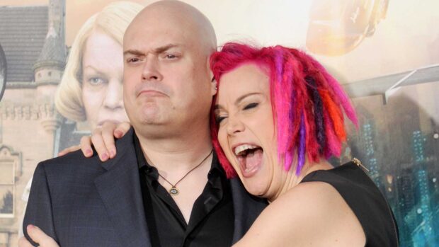A vibrant woman with colorful hair hugs a serious man at a public event, HD Desktop Wallpaper