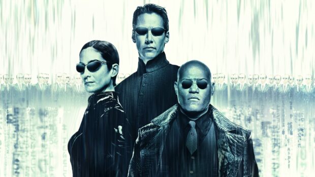 Lana Wachowski stands with characters in black attire and glasses, 2K Desktop Wallpaper