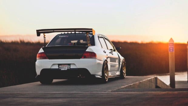 A white Lancer Evo car is parked near a riverside during sunset with a large rear wing, HD Desktop Wallpaper