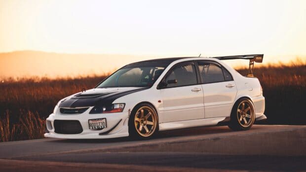 A white Lancer Evo is parked beside a road with golden hour sunlight, HD Desktop Wallpaper