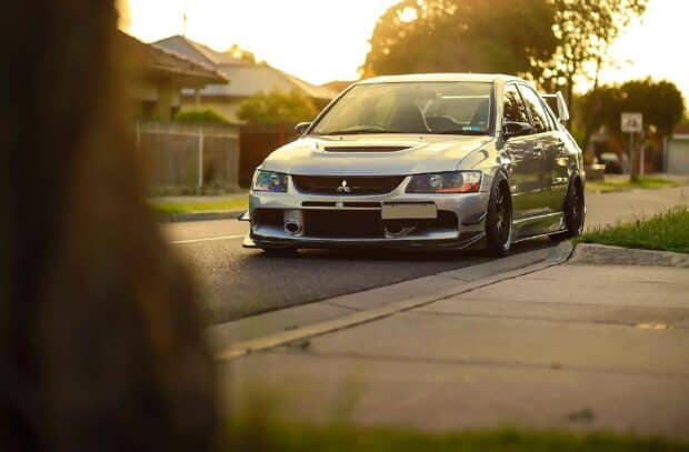 A silver Lancer Evo is parked on a quiet suburban street during sunset, HD Desktop Wallpaper
