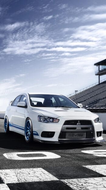 A white Lancer Evo is parked on a racing track under a partly cloudy sky, HD Phone Wallpaper