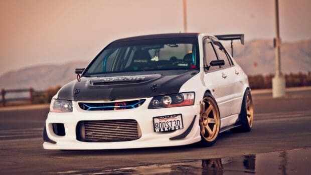 A Lancer Evo with a black hood and gold rims parked in an empty lot at sunset, HD Desktop Wallpaper