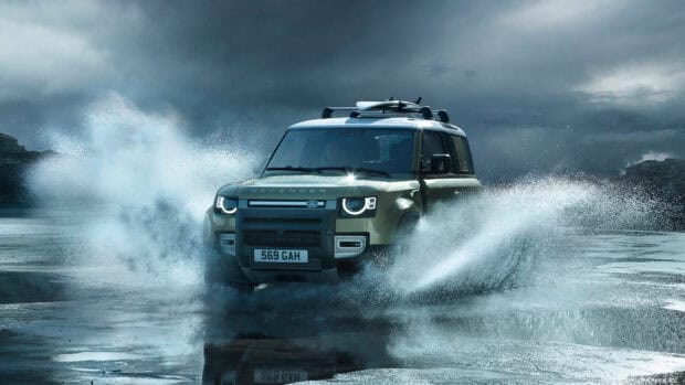 A Land Rover Defender drives powerfully through water and rocky landscape under a stormy sky, 4K Desktop Wallpaper