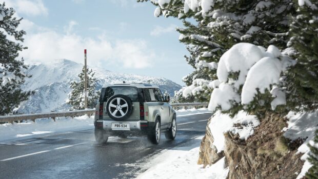 A Land Rover Defender drives on a snowy mountain road surrounded by snow covered trees, 4K Desktop Wallpaper