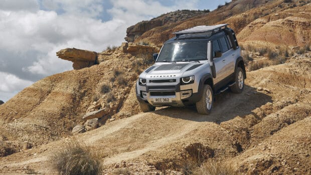 A Land Rover Defender driving on a rocky desert terrain under a cloudy sky, 4K Desktop Wallpaper