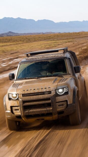 A Land Rover Defender driving fast on a dusty off road trail, 4K Phone Wallpaper