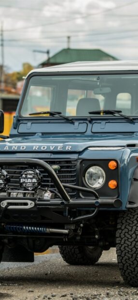 A blue Land Rover Defender is parked with visible front grill and lights, HD Phone Wallpaper