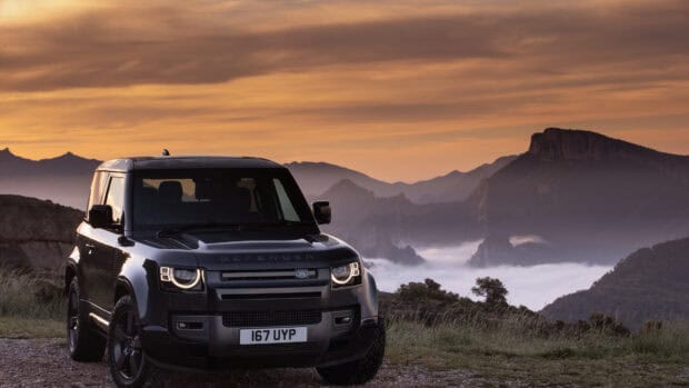 A Land Rover Defender drives near a misty mountain landscape at sunset, 4K Desktop Wallpaper