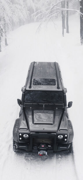 A Land Rover Defender moves through a snowy forest trail during winter, HD Mobile Wallpaper