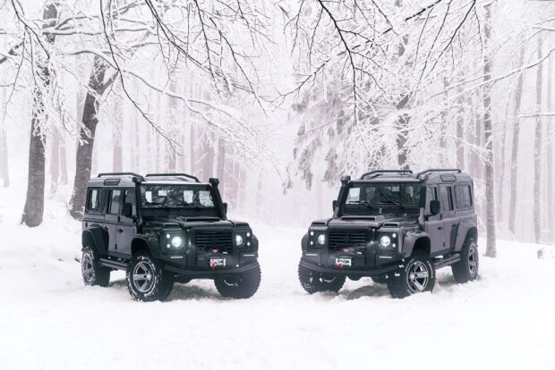 Two Land Rover Defender vehicles stand in a snowy forest landscape during winter, HD Desktop Wallpaper